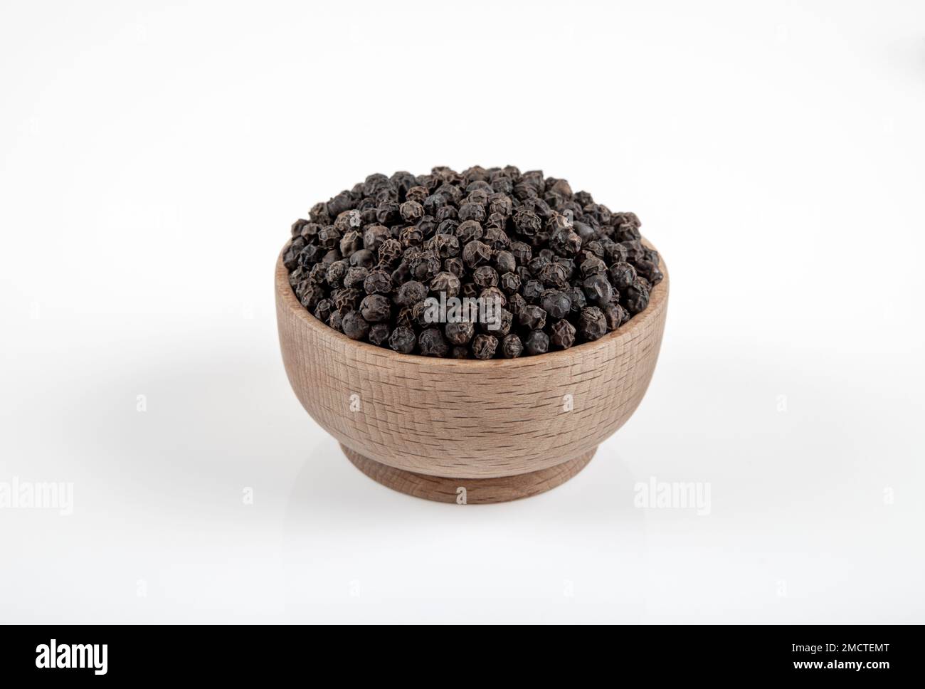 Schale voll mit schwarzem Pfeffer auf weißem Hintergrund Stockfoto