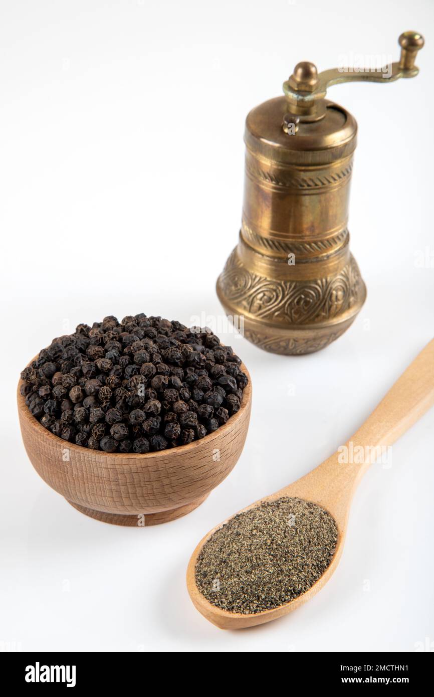 Schwarze Pfefferkörner, gemahlener schwarzer Pfeffer und Metallmühle auf weißem Hintergrund Stockfoto