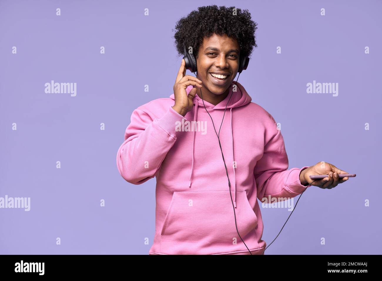 Fröhlicher afroamerikanischer Teenager mit Kopfhörern und Handy. Stockfoto