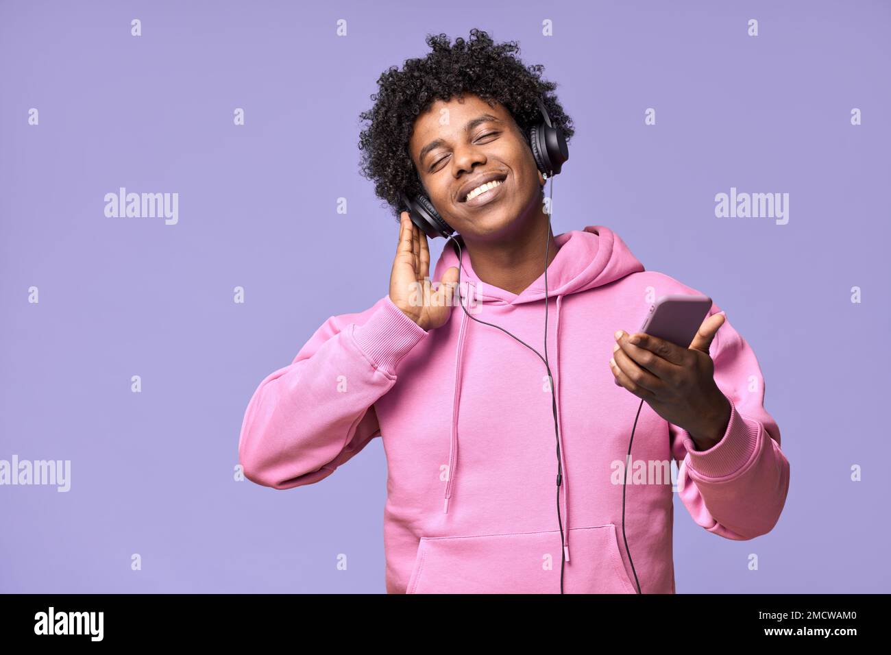 Ein glücklicher Afroamerikaner, der Kopfhörer trägt und mobile Musik hält. Stockfoto