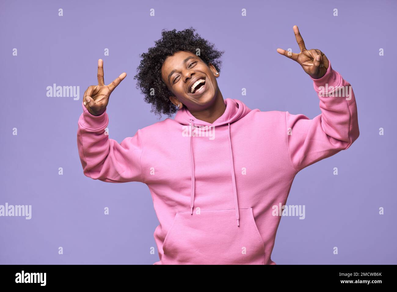 Ein fröhlicher, cooler afroamerikanischer Teenager, der ein Friedenszeichen zeigt, isoliert auf lila. Stockfoto