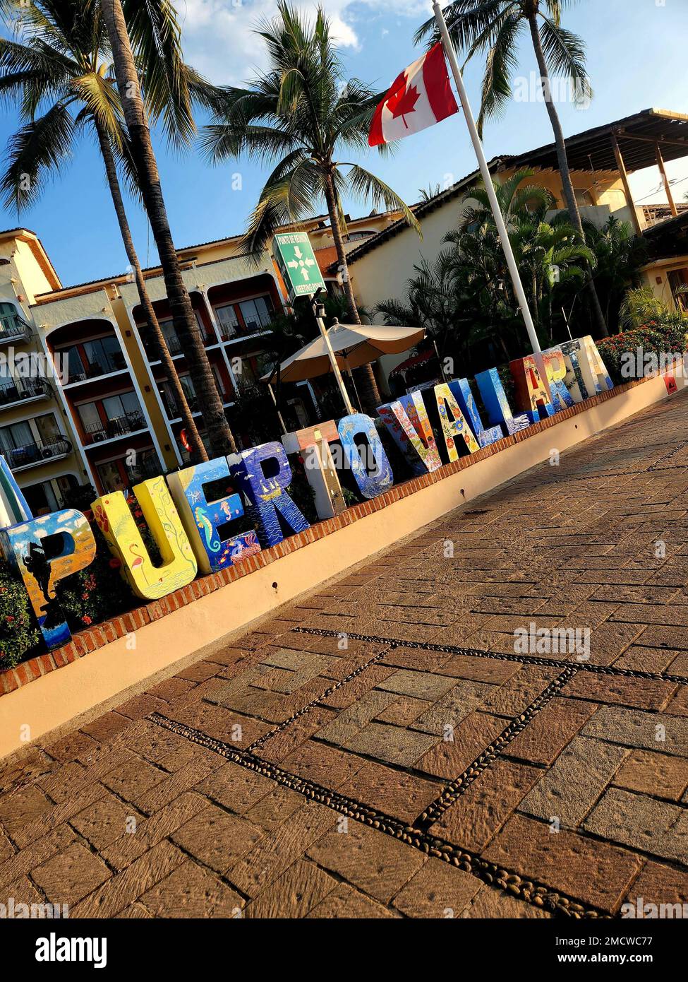 Ein vertikales Bild des farbenfrohen Stadtzeichens von Puerto Vallarta und der Flagge Kanadas Stockfoto