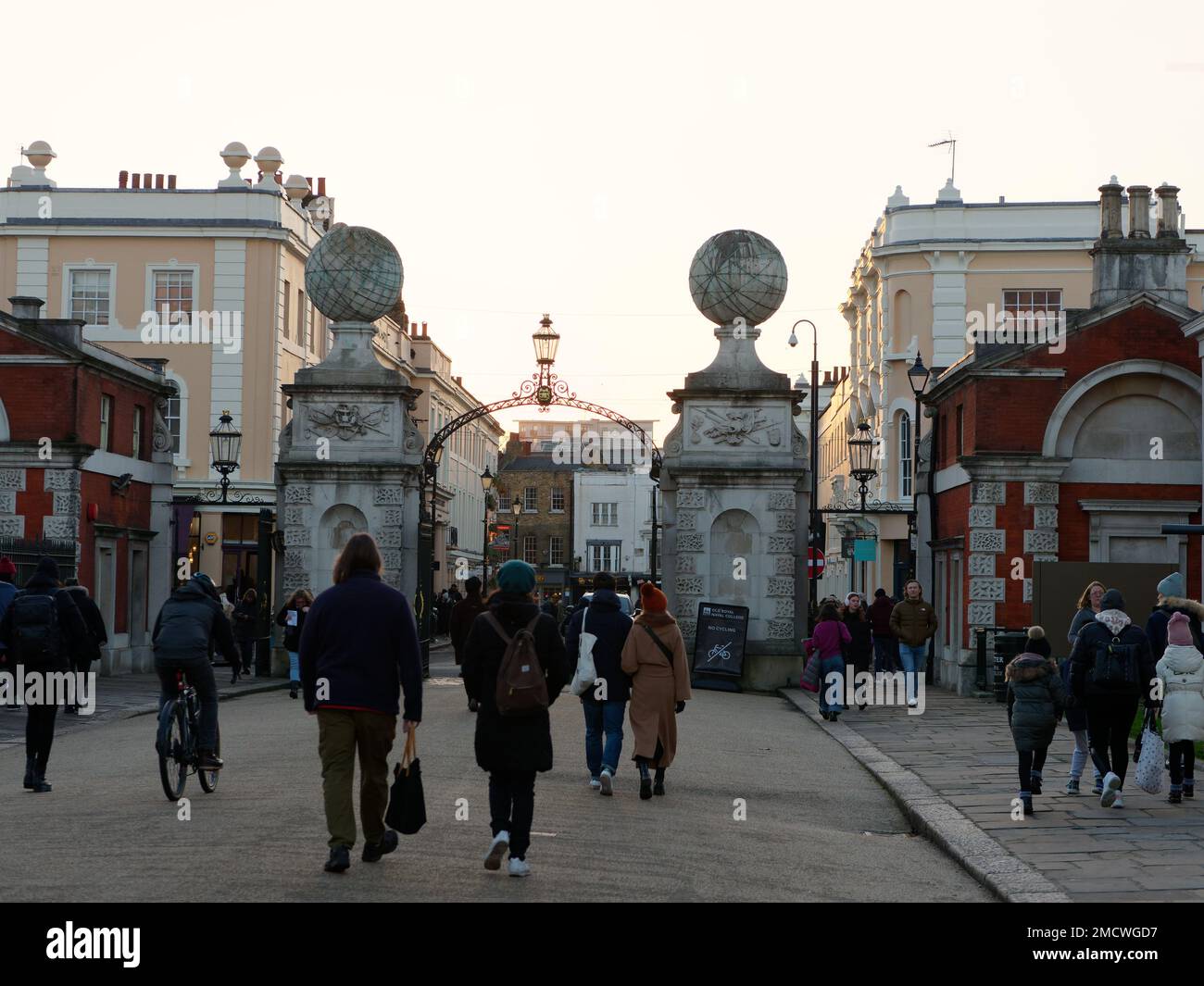 An einem Wintertag mit Gebäuden auf beiden Seiten gehen Leute in Richtung eines steinernen Tors im Zentrum von Greenwich Town. London, England Stockfoto