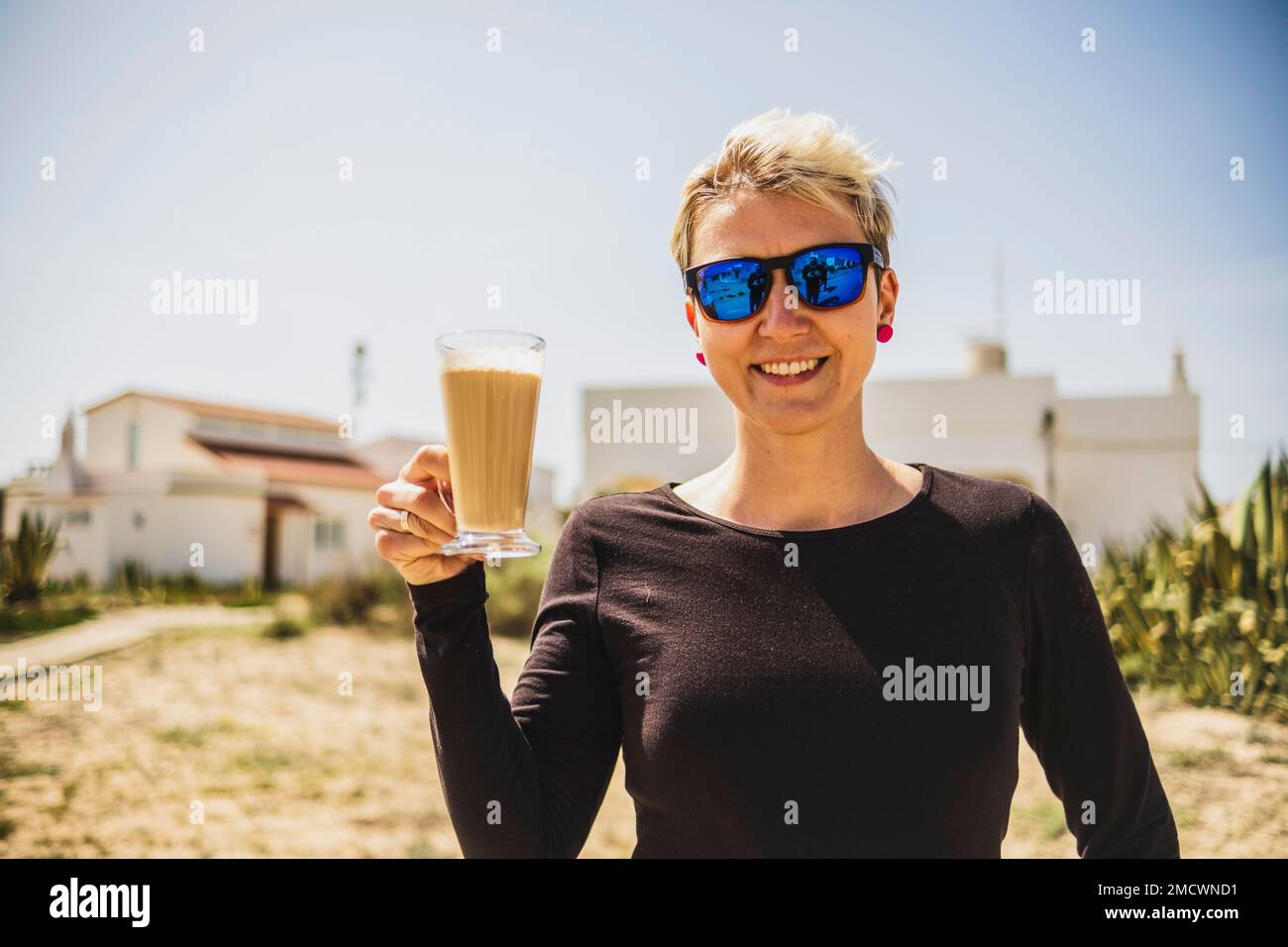 Glückliche Frau mit großem Kaffee mit Milch während des Urlaubs in Portugal Stockfoto