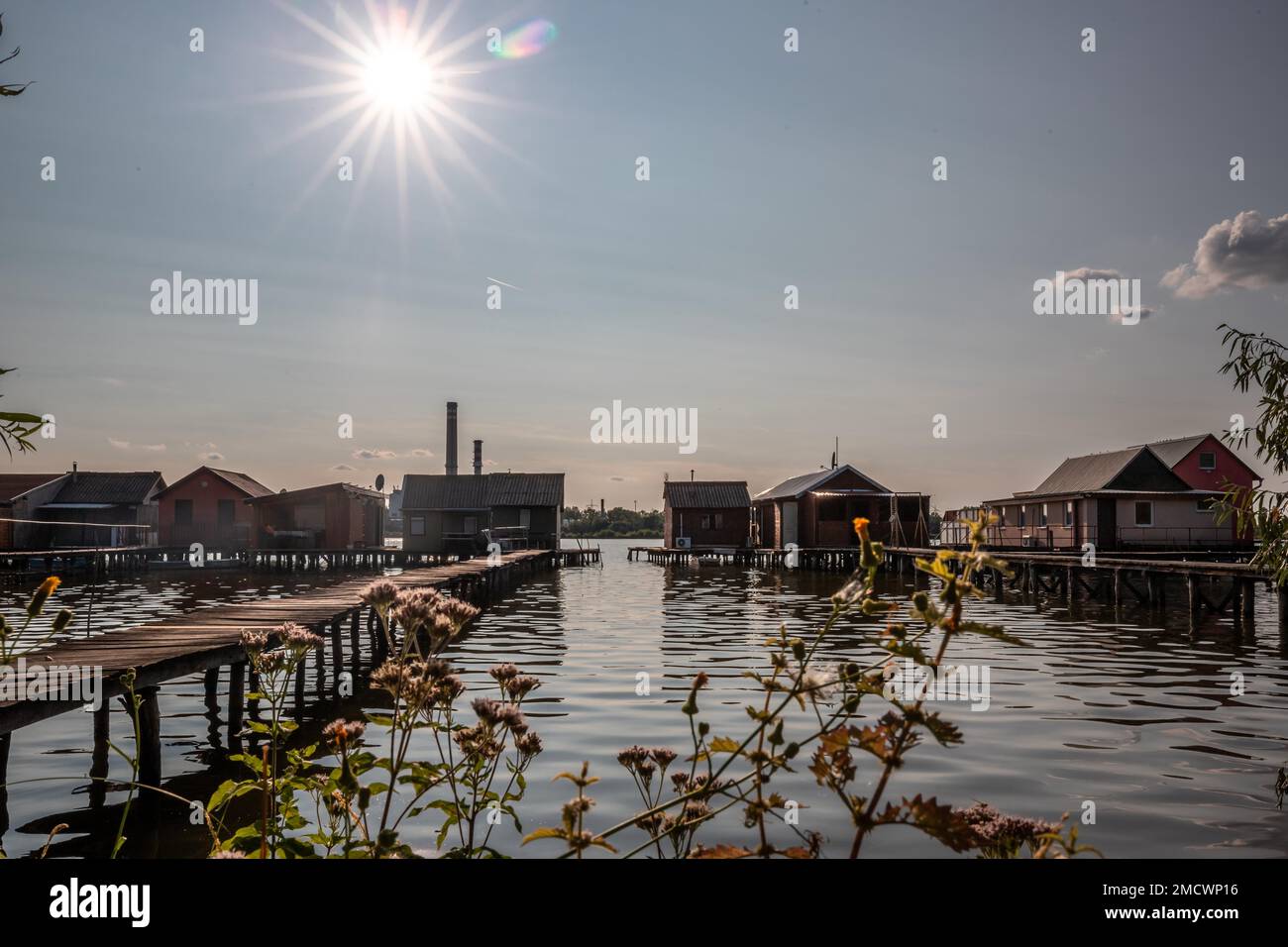 Kleine Holzhäuser mit einem Steg in einem See dienen als Angeln- und Ferienhäuser für Ungarn. Wunderschönes Landschaftsfoto bei Sonnenuntergang, Lake Bokodi Stockfoto
