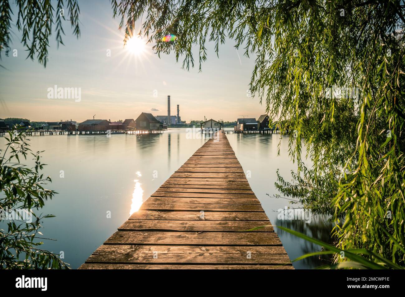 Kleine Holzhäuser mit einem Steg in einem See dienen als Angeln- und Ferienhäuser für Ungarn. Wunderschönes Landschaftsfoto bei Sonnenuntergang, Lake Bokodi Stockfoto