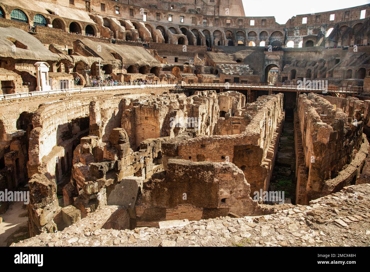 Touristen erkunden das Innere des Kolosseums in Rom, Italien, mit seinen exponierten unterirdischen Strukturen. Stockfoto