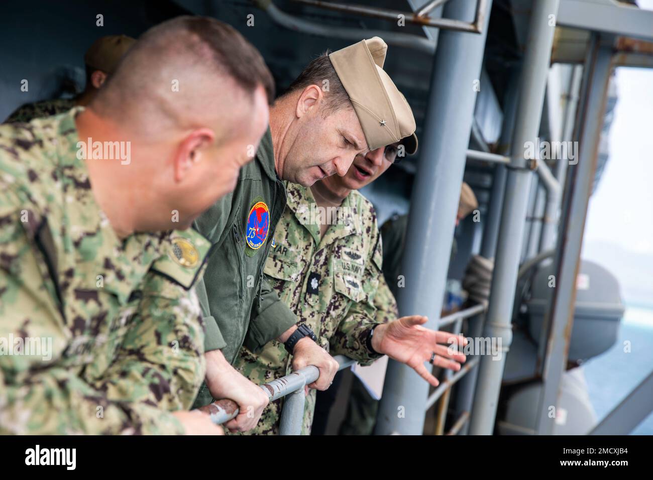 APRA-HAFEN, Guam – Cmdr. Bryan Kupyar, Right, Executive Officer des U-Boot-Tenderschiffs USS Emory S. Land (AS 39), gibt eine Schiffstour nach Rear ADM. Mark Melson, Center, Commander, Logistics Group Western Pacific/Commander, Task Force 73, Center, Juli 11. Land hat die Aufgabe, schnelle Wartungs- und Reparaturarbeiten auf mittlerer Ebene durchzuführen sowie Hotelservice und Logistikunterstützung für bereitgestellte geführte Raketen und Schnellangriff-U-Boote bereitzustellen, die in Zuständigkeitsbereiche der US-5.- und US-7.-Flotte eingesetzt werden. Stockfoto