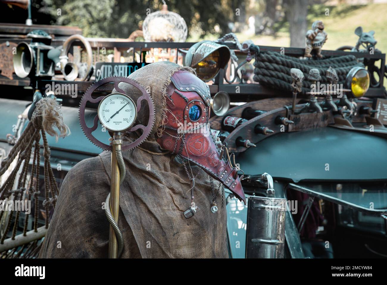 Eine Figur mit Pestmaske, die vor einem Fahrzeug steht. Postapokalyptisches oder dystopisches Thema. Stockfoto