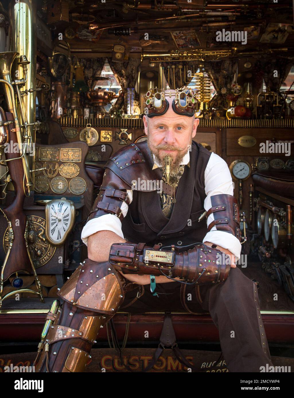 Ein Steampunk befindet sich an der Seite seines VW-Wohnwagens und zeigt das herrliche Interieur. Science-Fiction, Abenteurer, Zeitreisenkonzept. Stockfoto