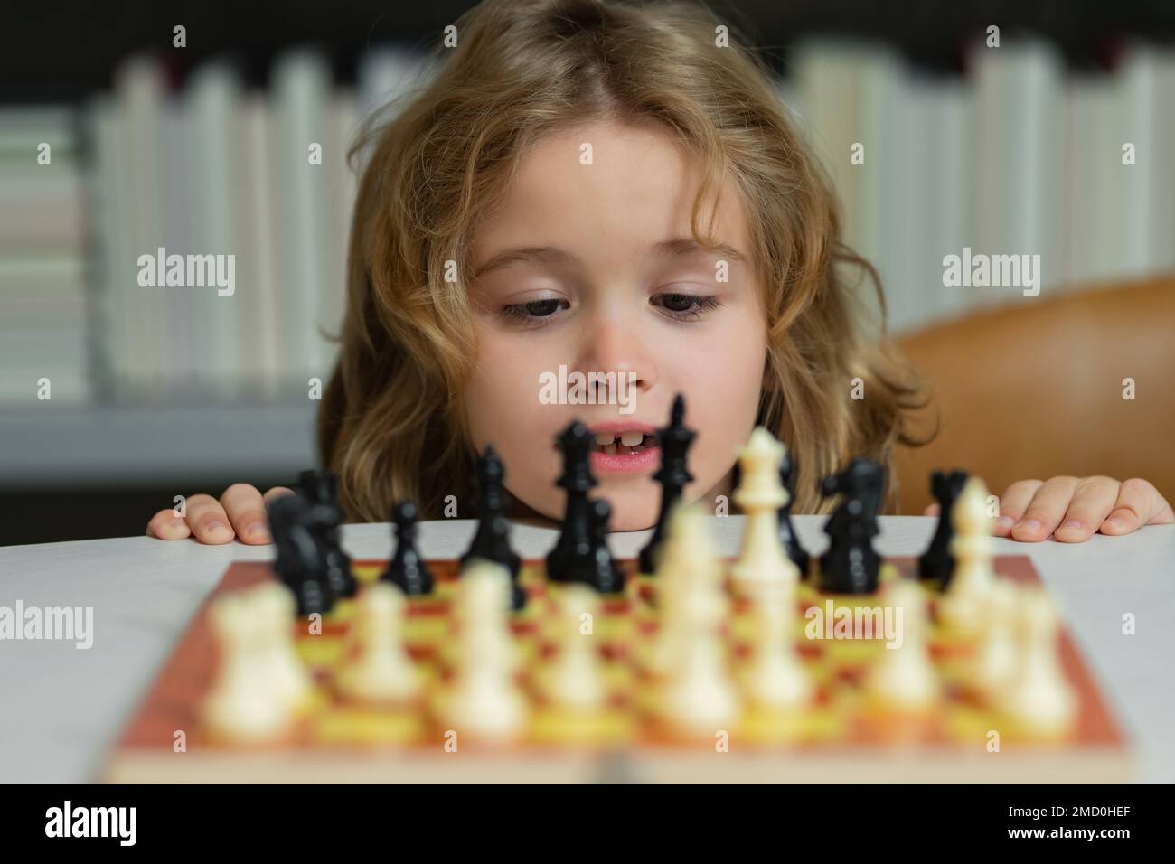Kleines Kind spielt Schach. Kind spielt Brettspiel. Denk-Kind-Brainstorming und Idee im Schachspiel. Kinder Frühentwicklung. Ein Junge, der Schach spielt Stockfoto
