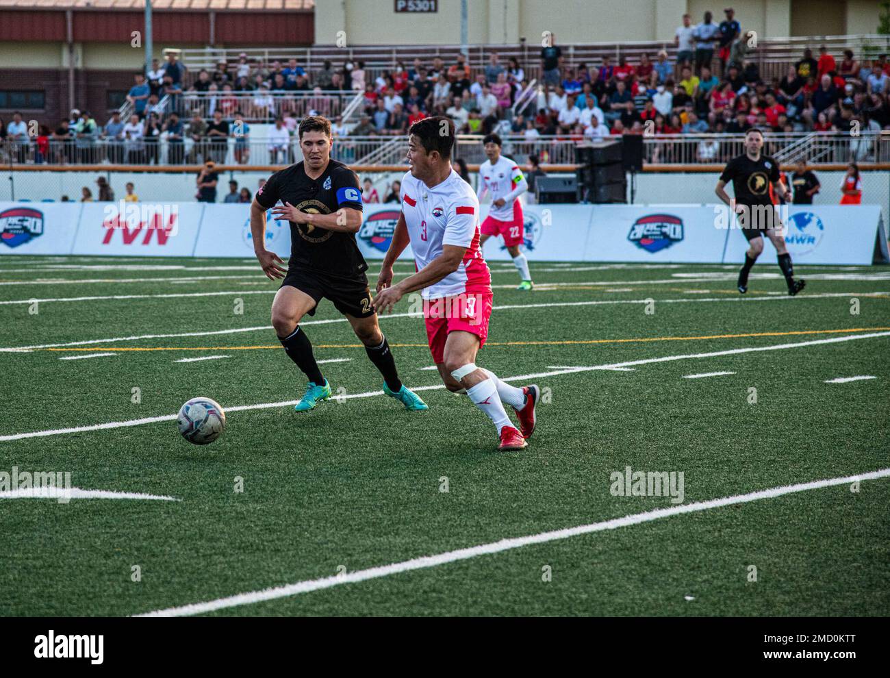 USA Air Force-Kapitän Jason Hoist mit 604. Air Support Operation Squadron holt seinen Gegner beim Camp Humphreys Legends Soccer Match in der Humphreys Middle School am 11. Juli 2022 ein. Die Veranstaltung wurde durchgeführt, um Kameradschaft und Freundschaft zwischen dem US-Militär und Südkorea zu stärken. Stockfoto