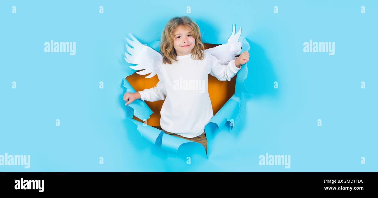 Kinderengel im Papierloch. Porträt eines Engelskindes. Kleiner Amor mit weißen Flügeln. Weihnachtskinder. Stockfoto
