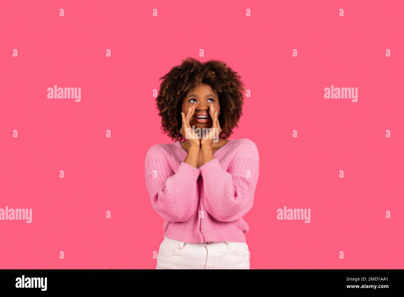 Fröhlich, ziemlich witzig, junge afroamerikanische Locke, weiblich in lässiger Kleidung, flüsterndes Geheimnis, Blick auf freien Raum Stockfoto