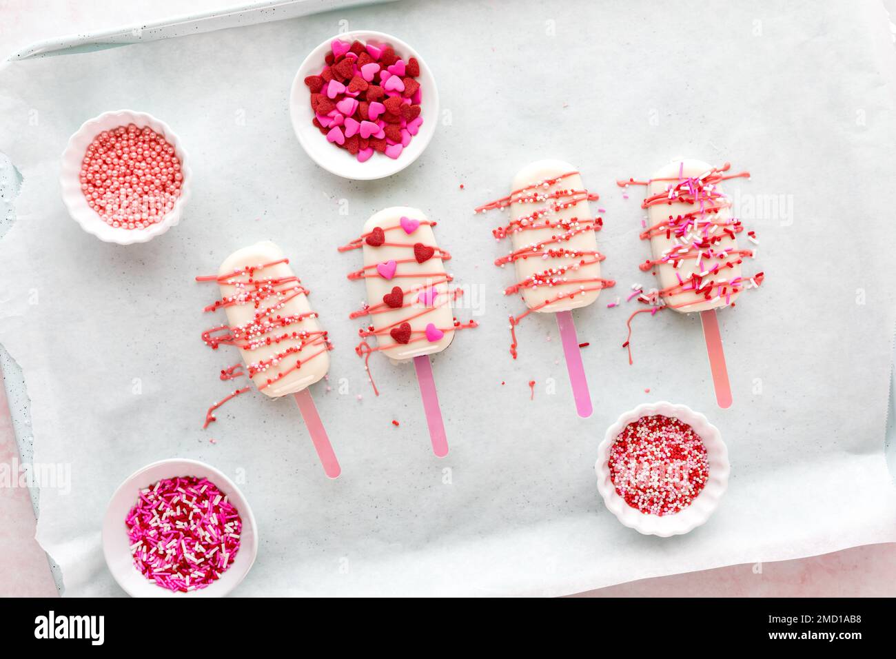 Frisch dekorierte hausgemachte Valentinscakesicles mit Süßigkeiten und Streuseln. Stockfoto