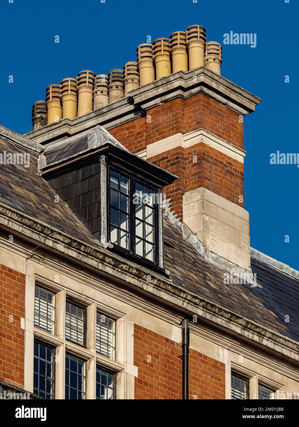 Chimney Pots London – mehrere Schornsteintöpfe auf einem Gebäude im Londoner Stadtteil Fitzrovia. Mehrere Schornsteine haben separate Schächte und jeder hat einen Topf. Stockfoto