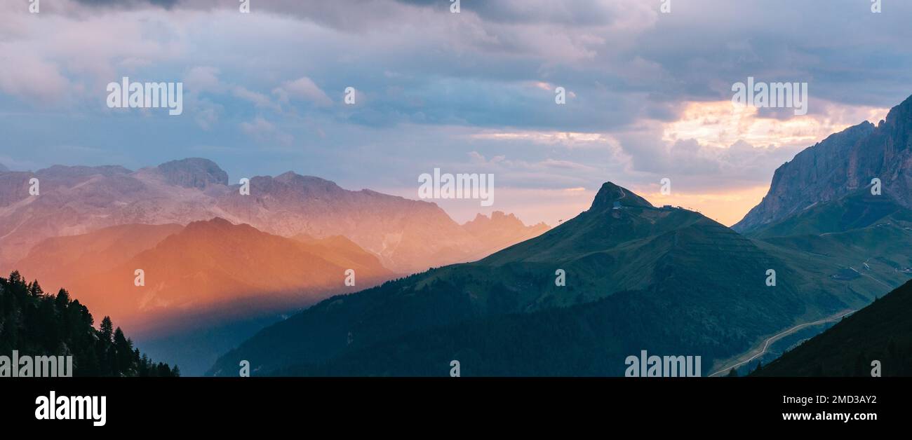 Ein filmreifes Panorama einiger Berge mit einem magischen orangefarbenen Lichtstrahl, der von der Sonne erzeugt wird. Italienische Alpen, Dolomiten, Italien. Beliebtes Reiseziel Stockfoto