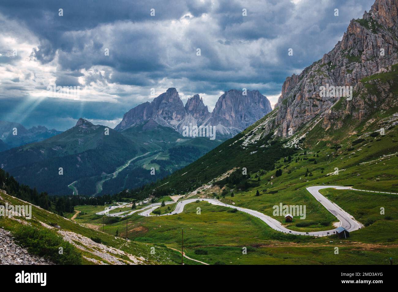 Bergpass in den italienischen Alpen mit einer gewundenen Straße, grünen Wiesen und majestätischen Bergen im Hintergrund. Bergstraße, beliebtes Reiseziel Stockfoto
