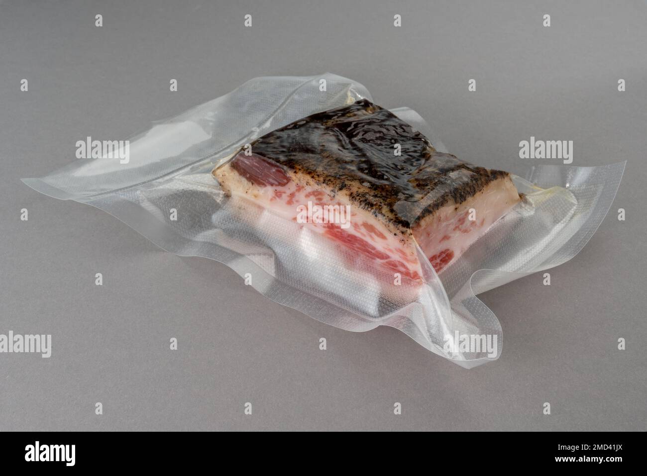 Guanciale Schweinebacken in vakuumverpackter Verpackung, versiegelt für Sous-Vide-Kochen auf grauem Hintergrund Stockfoto