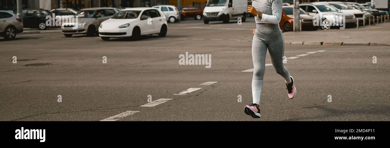 Sportlerin in hellgrau, aktive Kleidung, die tagsüber im Freien läuft Stockfoto