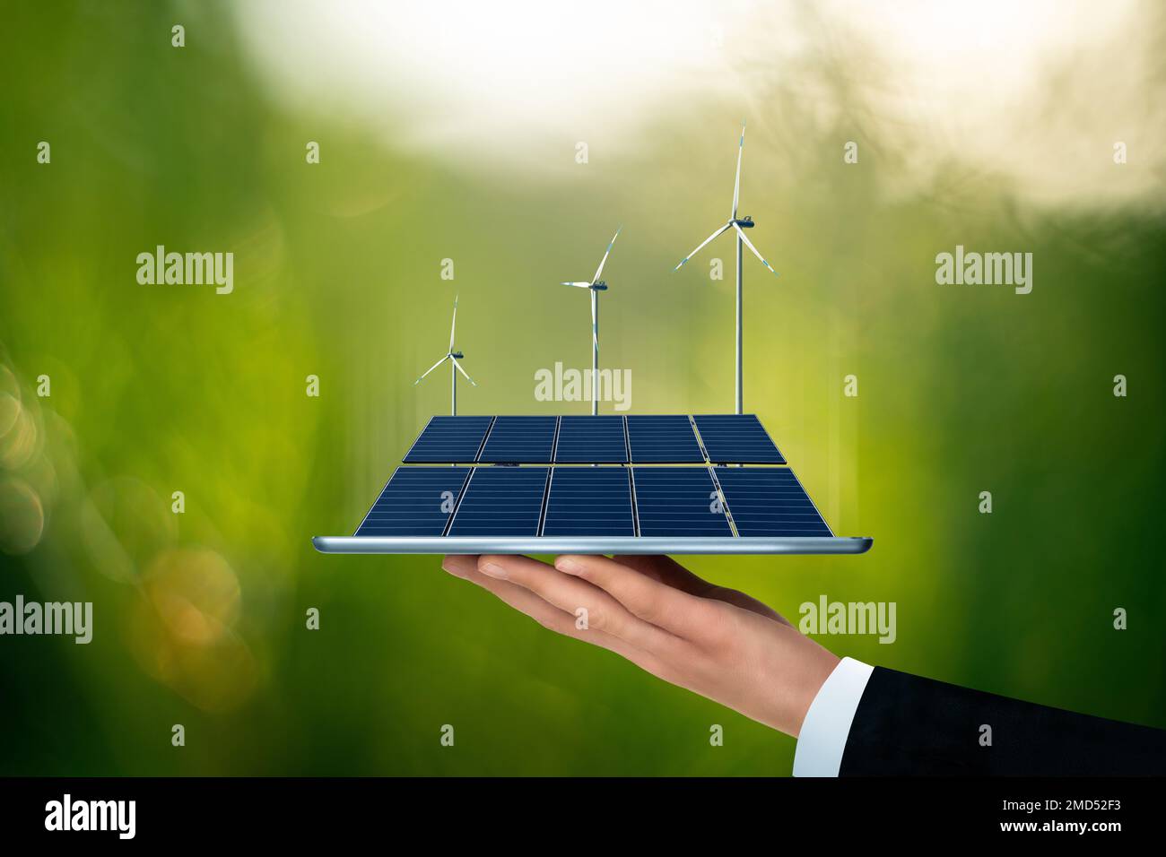 Ein Geschäftsmann hält ein digitales Tablet mit Solarpaneelen und Windturbinen. Nachhaltiges Geschäftskonzept Stockfoto