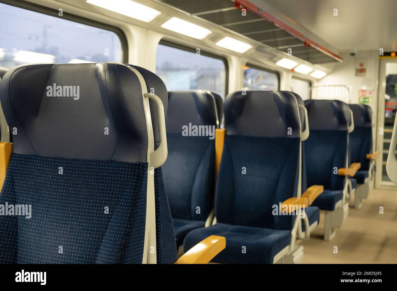 Moderner Personenzug für lange und kurze Entfernungen in Europa. Leeres Innere des Zugwaggons mit leeren blauen Sitzen für einen komfortablen Passagier Stockfoto
