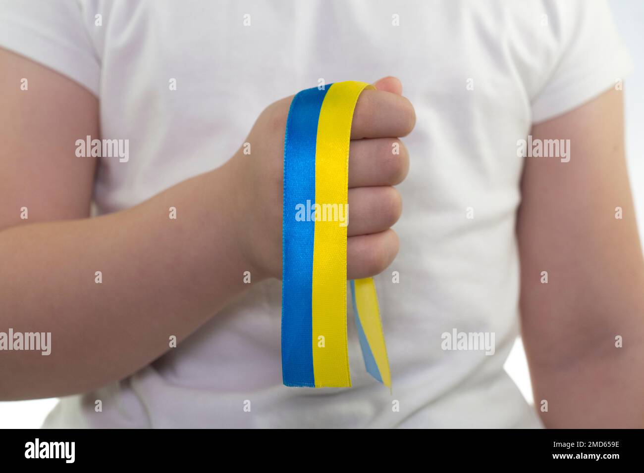 Ein Mädchen in einem weißen T-Shirt hält ein gelb-blaues Band in der Hand (Nahaufnahme). Staatsflagge der Ukraine. Nationales Symbol der Ukraine. Patriot Stockfoto