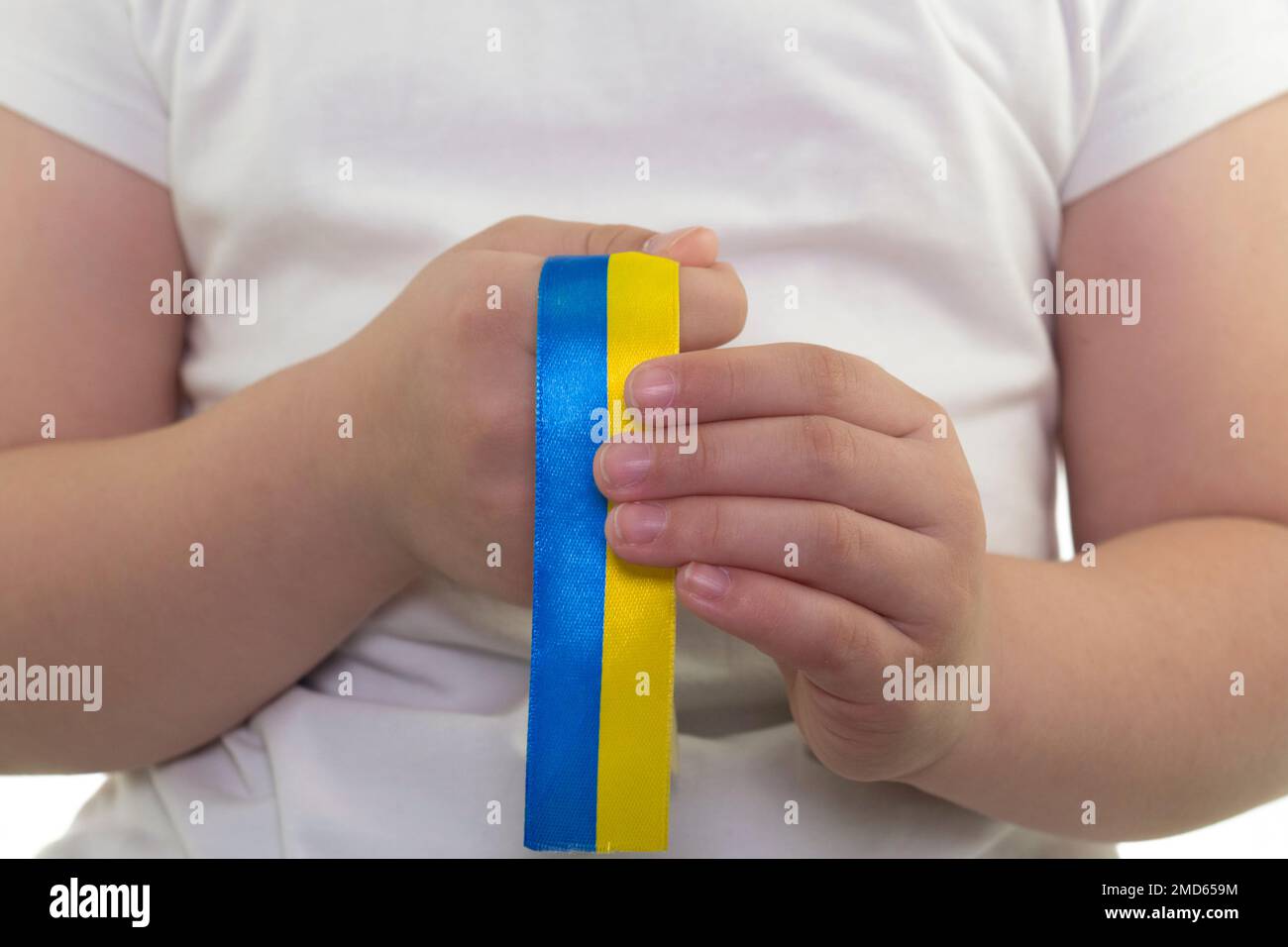 Ein Mädchen in einem weißen T-Shirt hält ein gelb-blaues Band in den Händen (Nahaufnahme). Staatsflagge der Ukraine. Nationales Symbol der Ukraine. Patriot Stockfoto