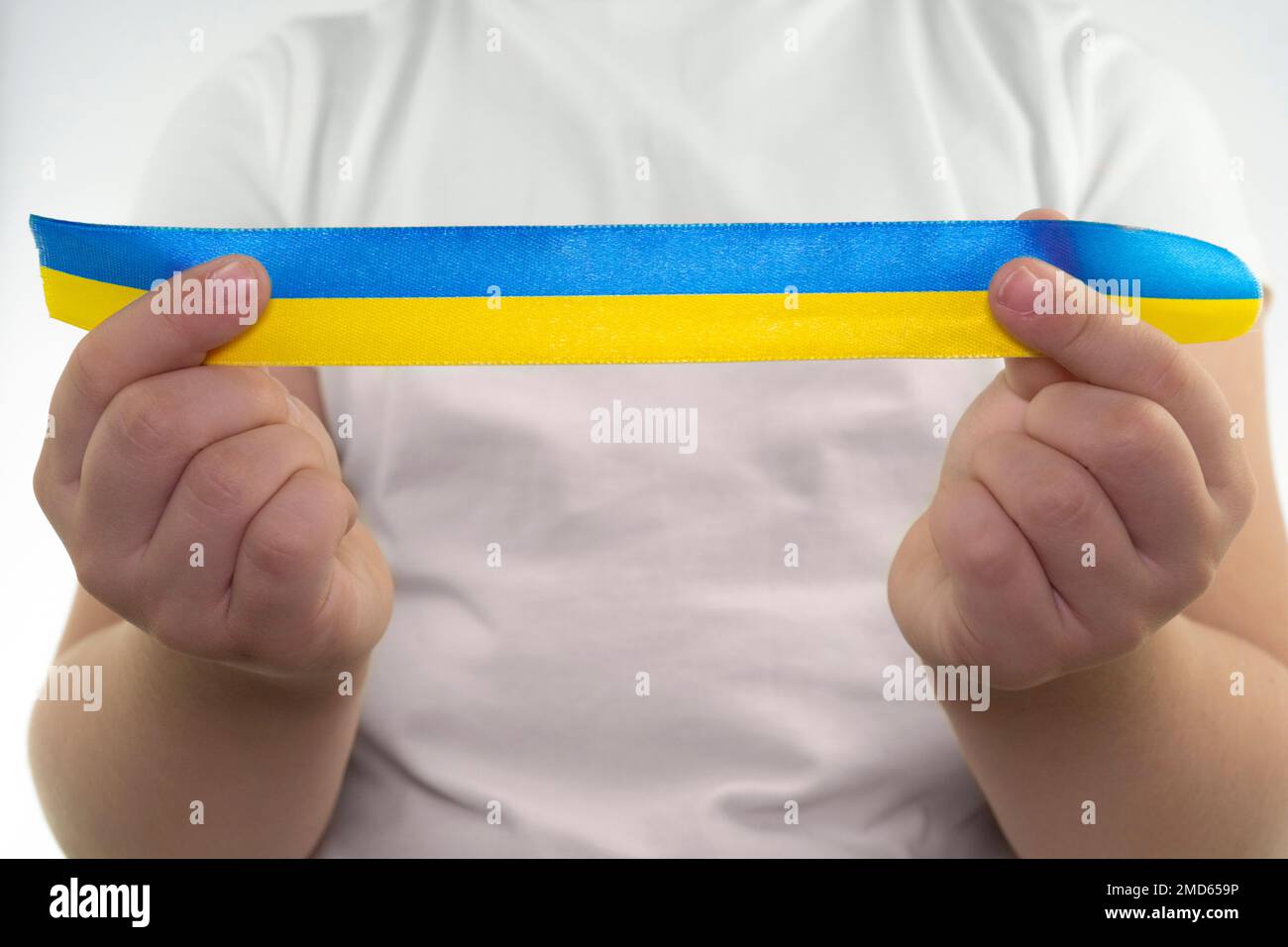 Ein Mädchen in einem weißen T-Shirt hält ein gelb-blaues Band in den Händen (Nahaufnahme). Staatsflagge der Ukraine. Nationales Symbol der Ukraine. Patriot Stockfoto