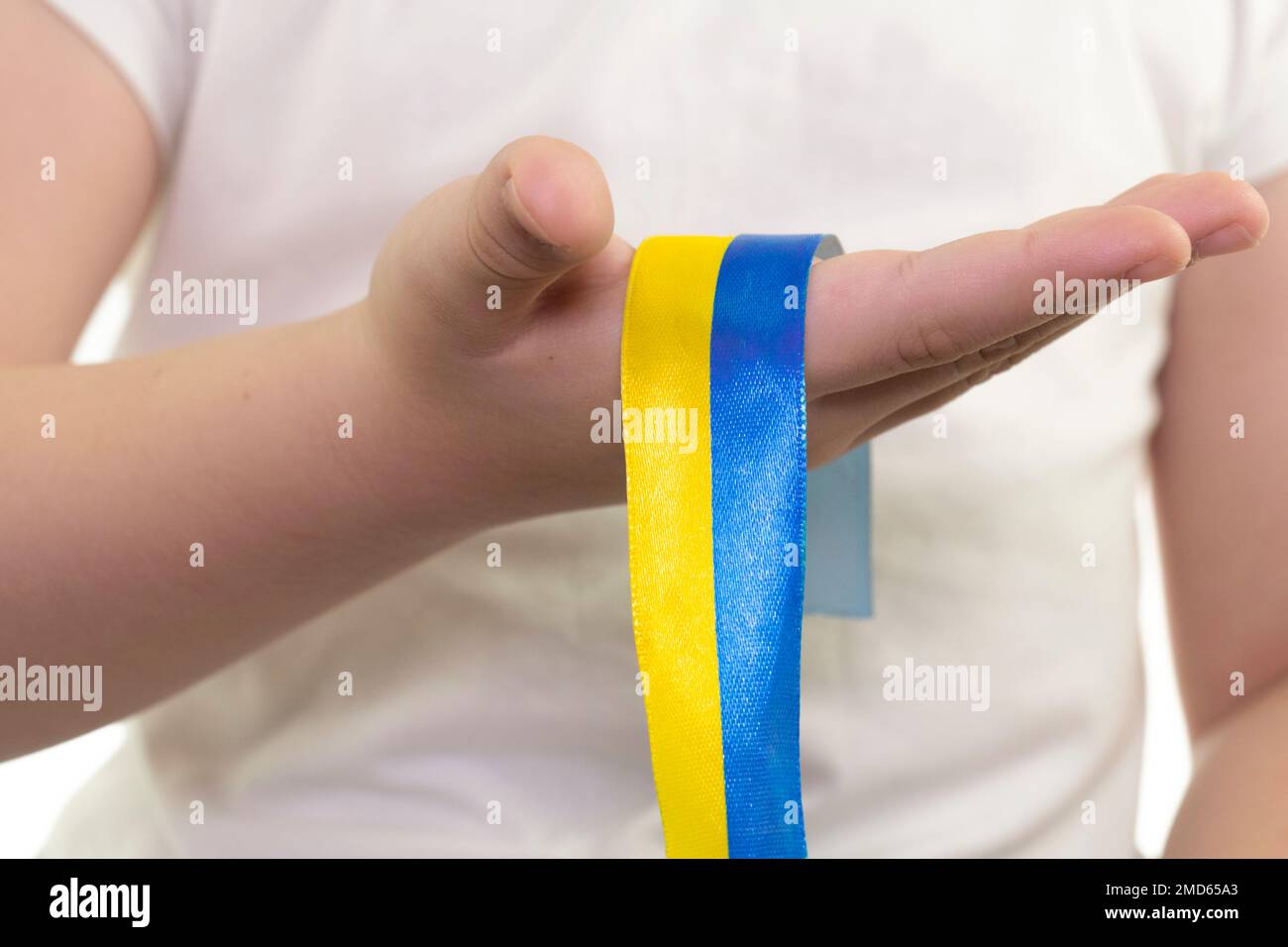 Ein Mädchen in einem weißen T-Shirt hält ein gelb-blaues Band in der Hand (Nahaufnahme). Staatsflagge der Ukraine. Nationales Symbol der Ukraine. Patriot Stockfoto