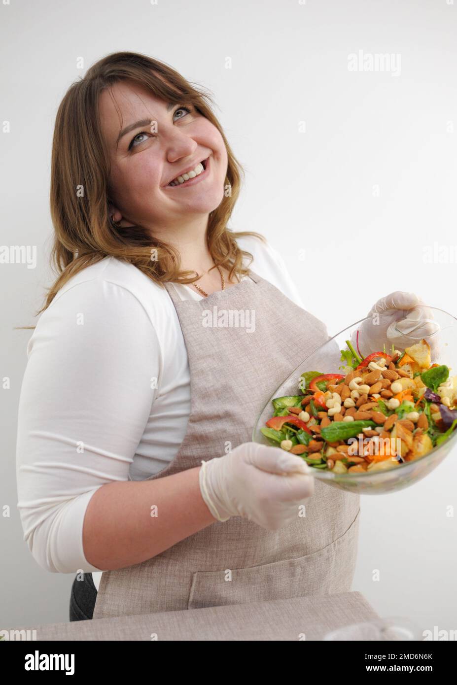 Erfolgreiches Werbefoto der schönen kurvigen Frau, die Salatdiät für Gewichtsverlust zubereitet vegetarische Lebensmittel köstlich gesunde weiße Hintergrundfläche für Text Banner Frau lächelnde weiße Zähne Stockfoto
