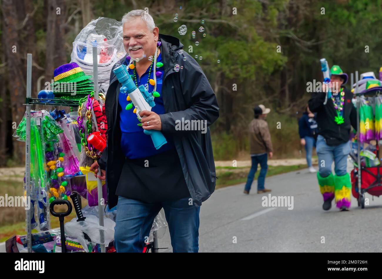 Bei der Mardi Gras-Parade auf Dauphin Island, Alabama, verkaufen Straßenverkäufer Blasengewehre und andere Schmuckstücke. Stockfoto