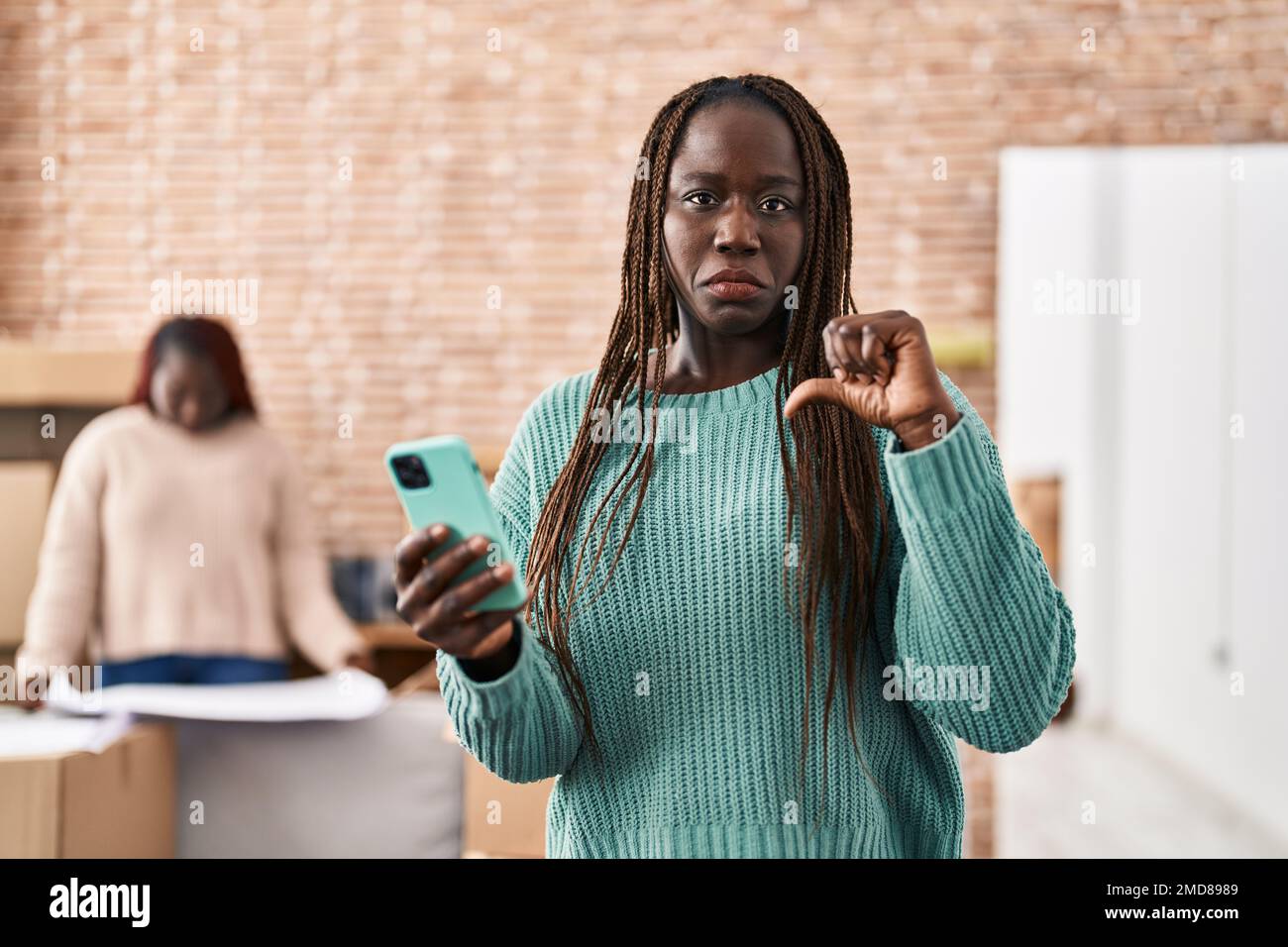 Afrikanische Frau, die in ihrem neuen Zuhause ein Smartphone benutzt ...