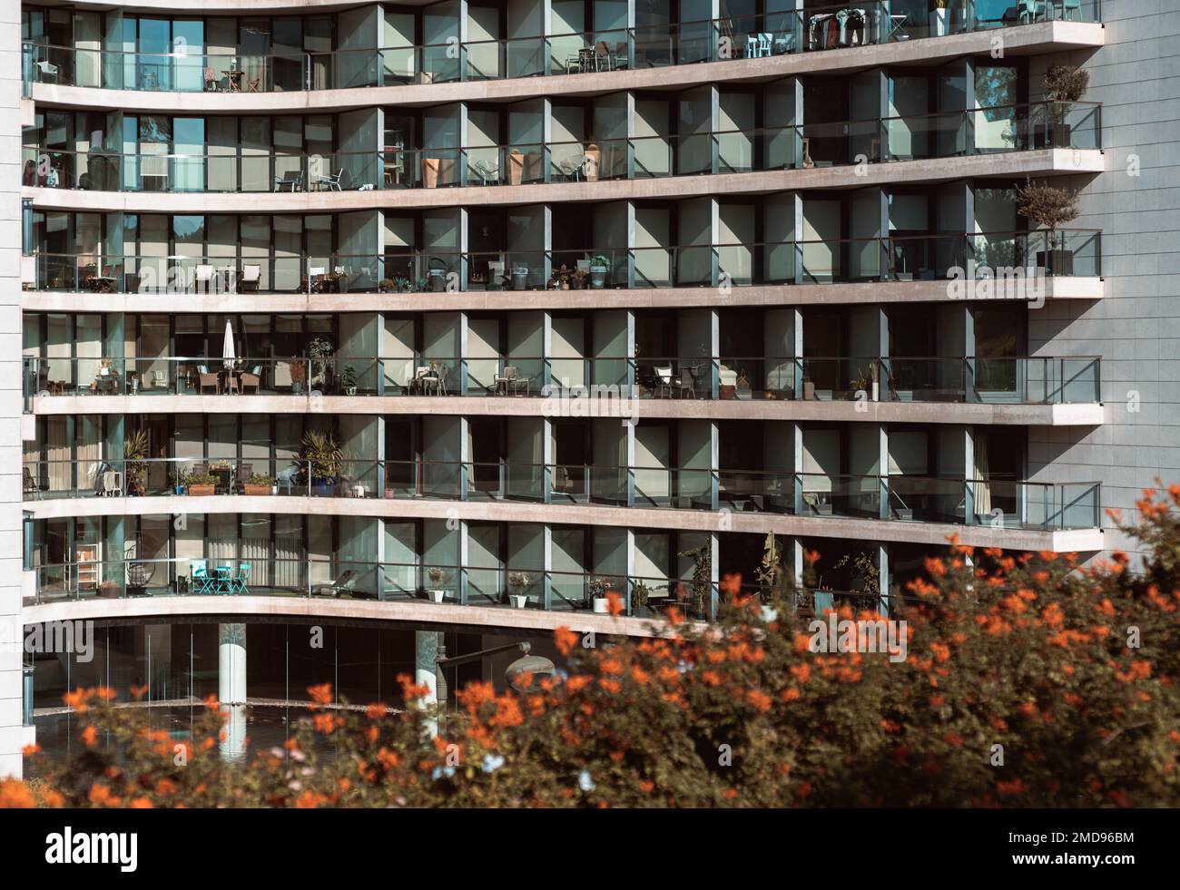 Die Glasfassade eines hohen, weißen Wohngebäudes mit Balkonen und gemusterten Fenstern und der strukturierte Hintergrund eines Wohnblocks Stockfoto