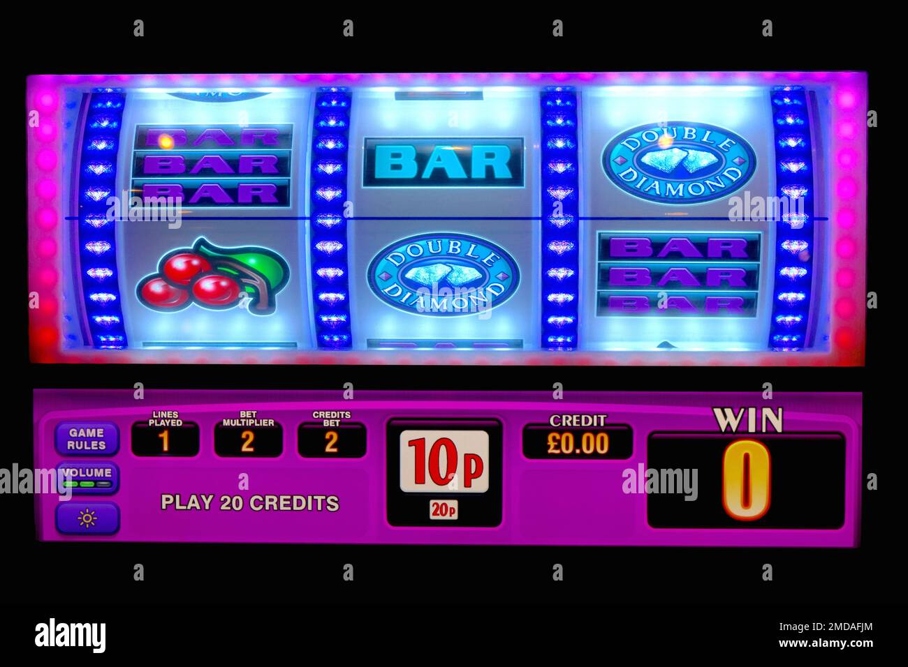 Farbenfrohe, beleuchtete Grafiken auf den Trommelrädern eines Spielautomaten ziehen Besucher mit blinkenden Lichtsequenzen in einem dunklen Vergnügungsviertel an. Stockfoto