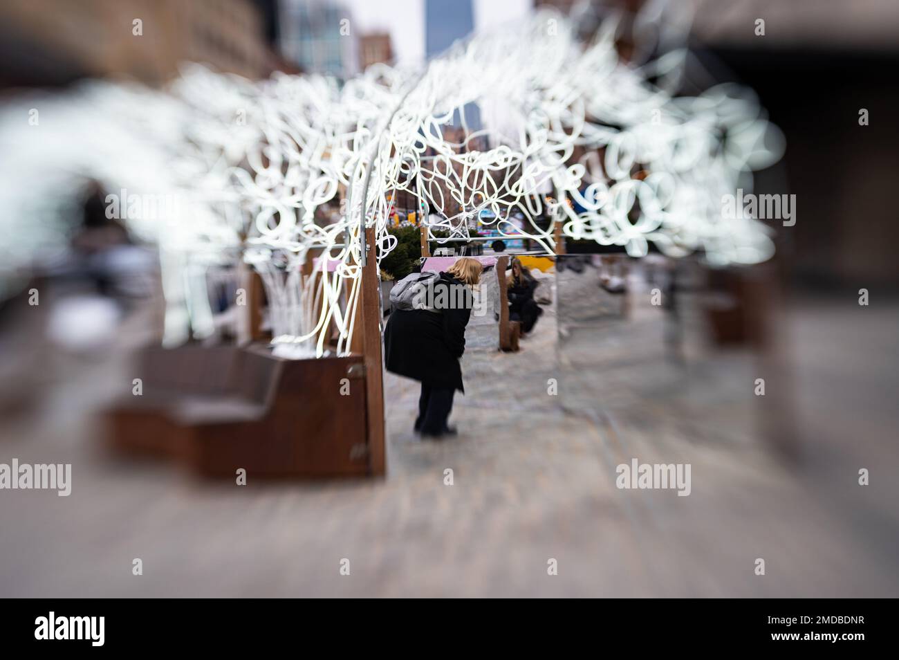 In einem selektiven Straßenfoto betrachtet sich die Tourist De Calvert in einem Spiegelabschnitt eines öffentlichen Kunstwerks im Meatpacking District. Stockfoto