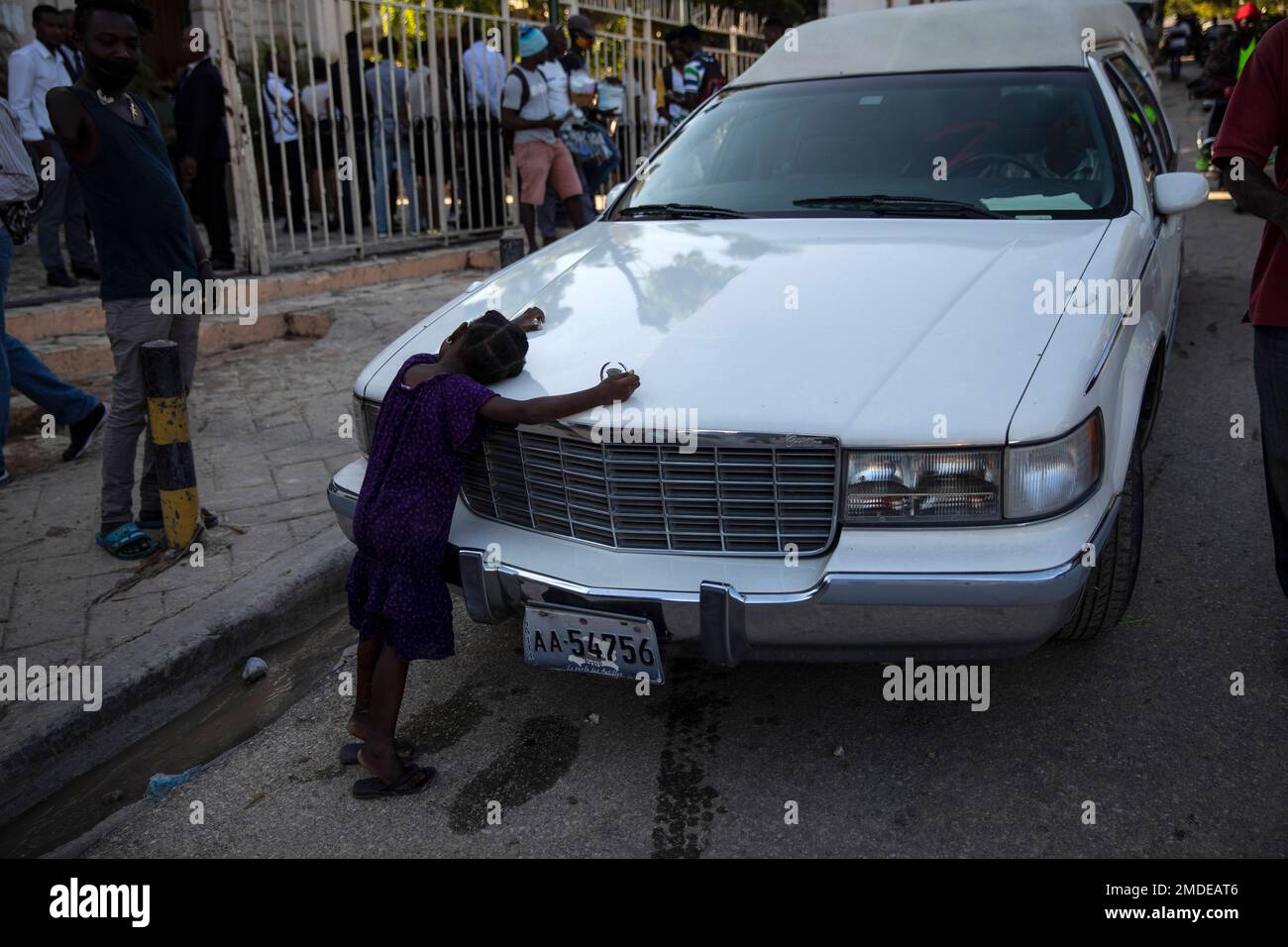 A girl rests on the hood of a hearse outside Saint Peter's church in Port-au-Prince, Tuesday, Sept. 28, 2021. (AP Photo/Rodrigo Abd) Stockfoto
