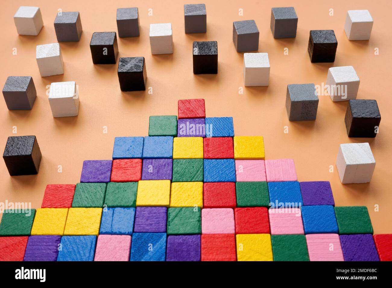 Inklusion oder Teambuilding-Konzept. Pyramide aus farbigen Würfeln und Schwarz-Weiß als nächstes. Stockfoto