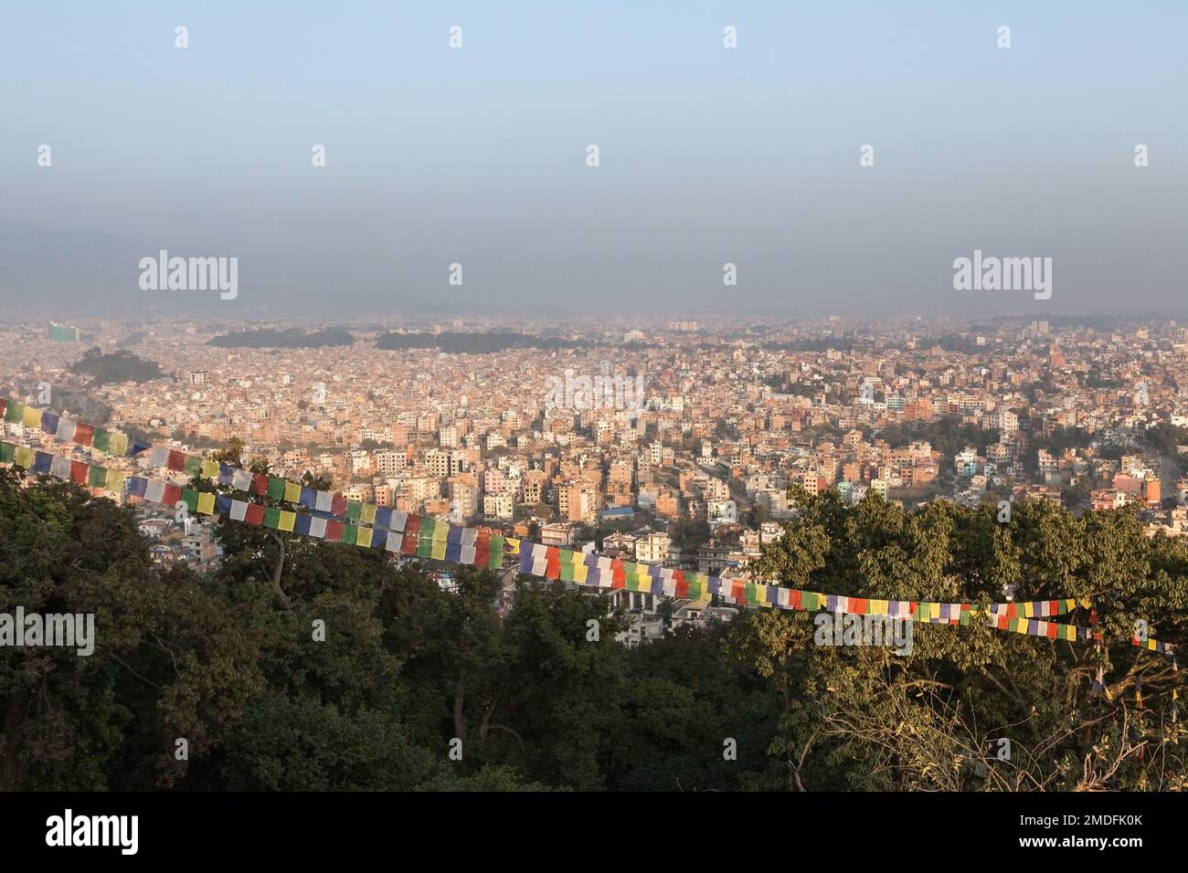 Luftaufnahme über die nepalesische Hauptstadt Kathmandu und buddhistische Gebetsflaggen vom Swayambhunath-Tempel. Große, riesige asiatische Stadt mit dichtem Smog bedeckt Stockfoto