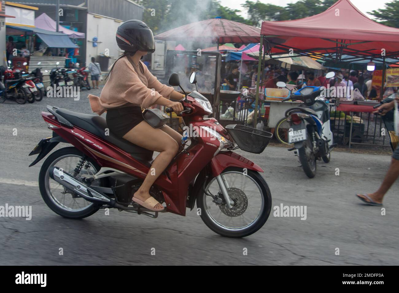 NAKHON NAYOK, THAILAND, 12 2022. JUNI, Eine Frau mit Helm fährt Motorrad Stockfoto