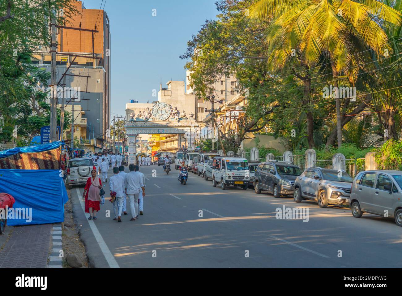 Puttaparthi, Andra Pradesh, Indien - 18,2023. Januar: Der junge Indianer in Weiß schließt den Spaziergang entlang der Straße zum Sai Baba Ashram Stockfoto