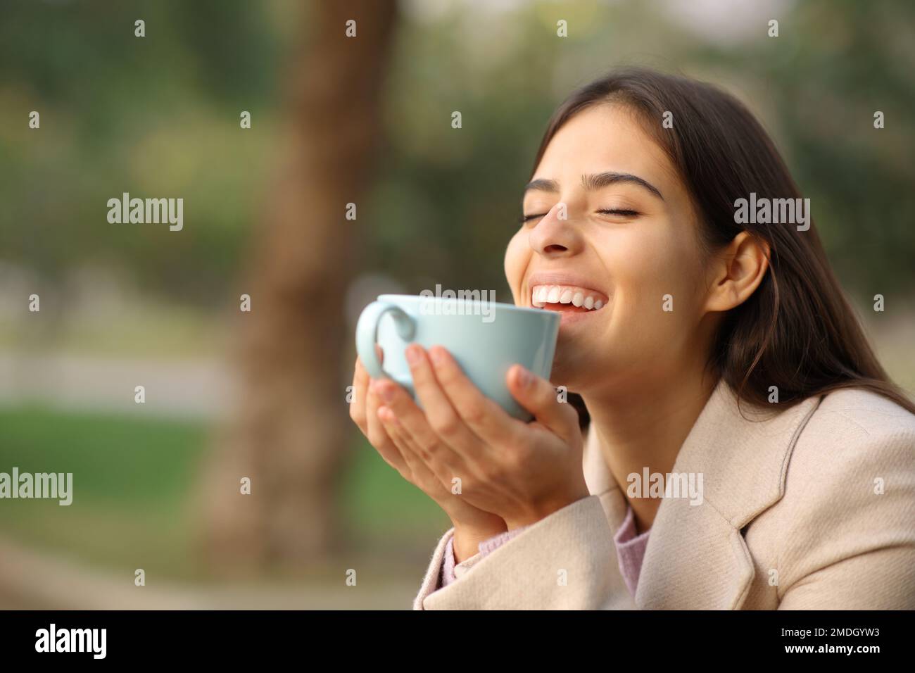 Glückliche Frau im Winter, die Kaffee genießt und im Park lacht Stockfoto