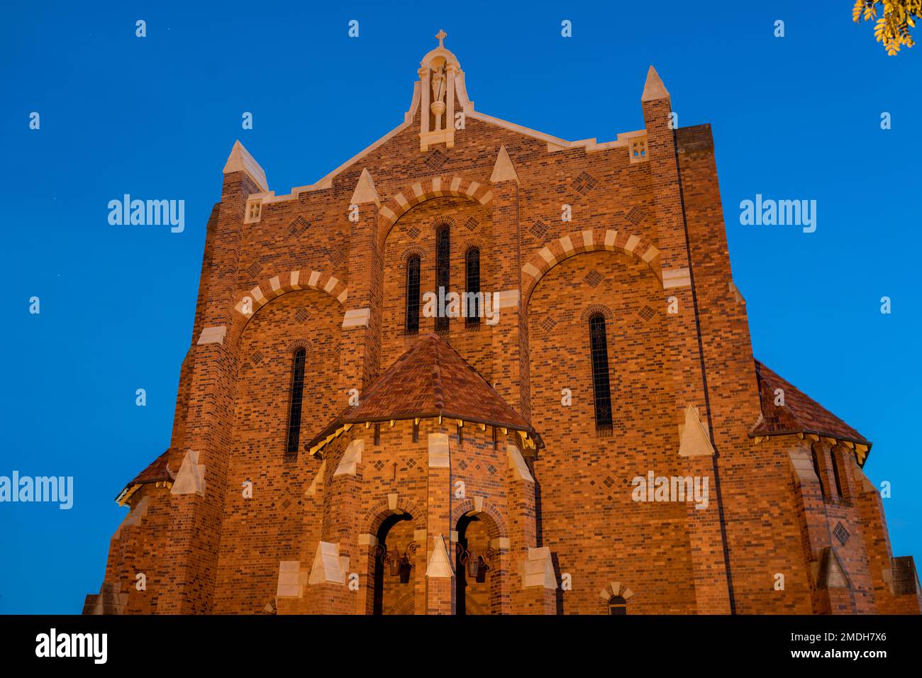 St. Brigid's Church strahlt majestätisch in bernsteinfarbenem Sonnenlicht, während die Sonne über dem Mount Cootha in Brisbane Queensland untergeht Stockfoto