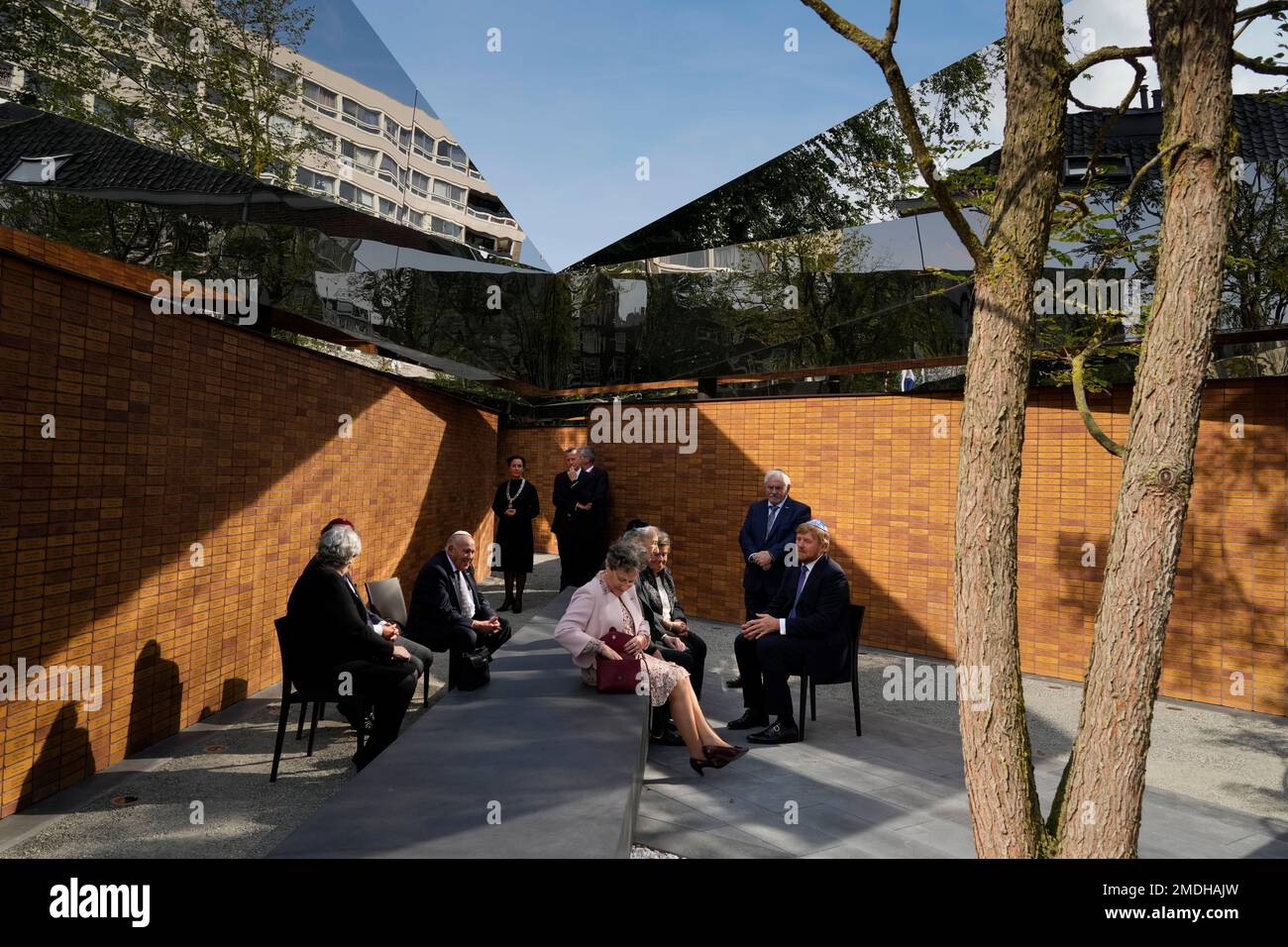 Holocaust survivors and relatives of victims sitting in front of a wall ...
