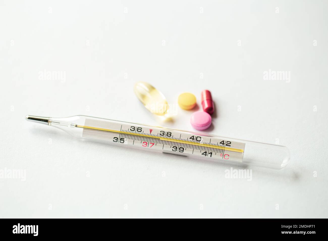 Thermometer und Pillen auf weißem Hintergrund, Nahaufnahme. Stockfoto