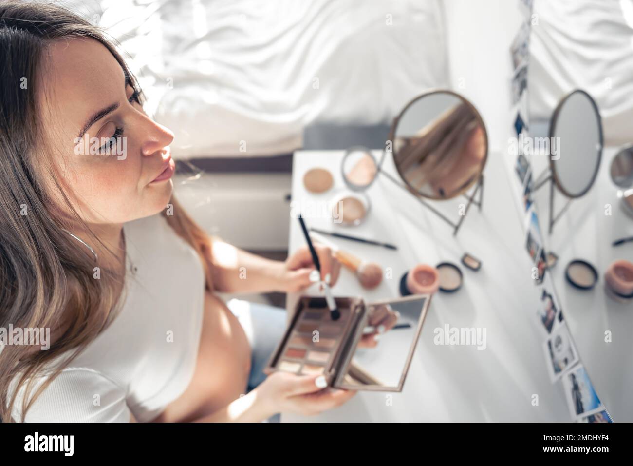 Eine schwangere Frau schminkt sich zu Hause vor dem Spiegel. Stockfoto