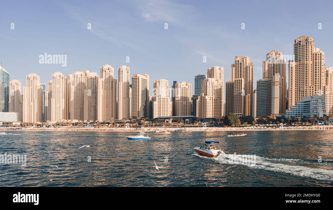 Panorama der Dubai Marina an einem Sommertag, VAE. Mit dem Schnellboot fahren Sie Touristen auf das Wasser in der Bucht in der Nähe der Küste von Dubai Stockfoto
