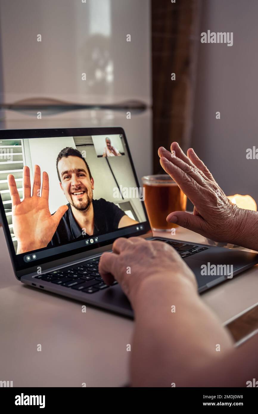 Eine alte Frau kommuniziert mit ihrem Sohn über eine Videoverbindung über einen Laptop. Stockfoto