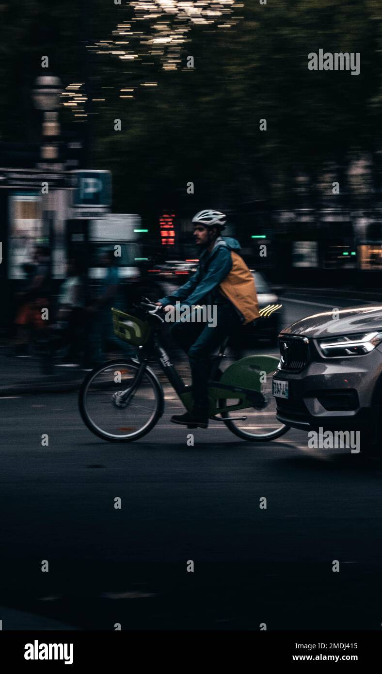 Eine Person, die an regnerischen Tagen in Paris, Frankreich, auf einem Bikel fährt, beim Schwenken Stockfoto