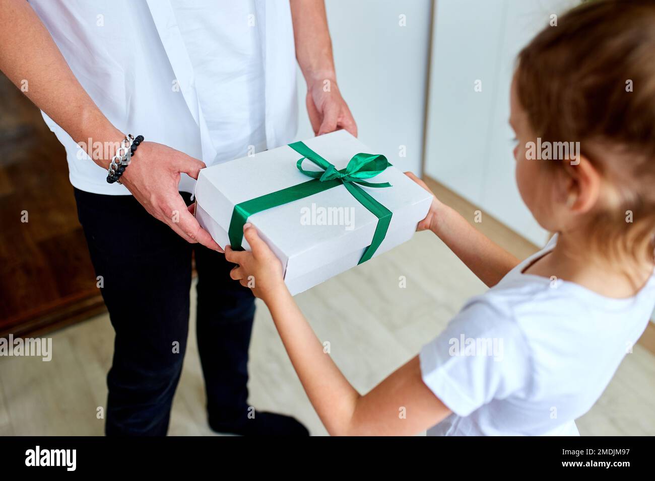 Kleines Mädchen gibt ihrem schönen Vater eine Geschenkbox am Vatertag, unerkennbare Tochter gratuliert Vater und Geschenke zum Geburtstag zu hom Stockfoto